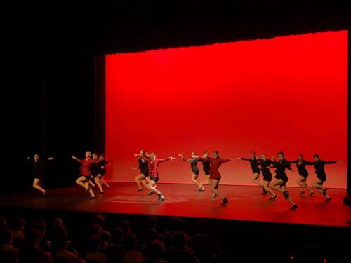 A group of dancers perform on a red stage