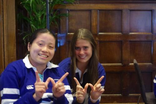 Two students in Women's jerseys pose at a debating competition
