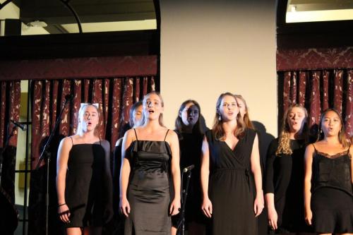 A group of singers in black perform for Group Vocal