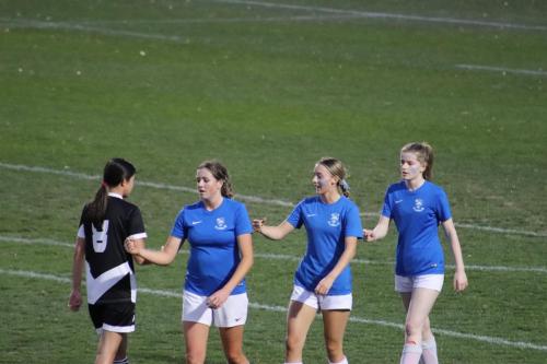 Four athletes congratulate each other on the field.
