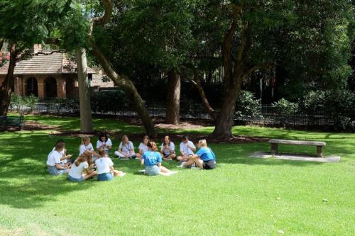 A group of students sit in a circle on grass.