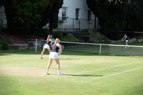 Two athletes prepare to receive a serve on a tennis court